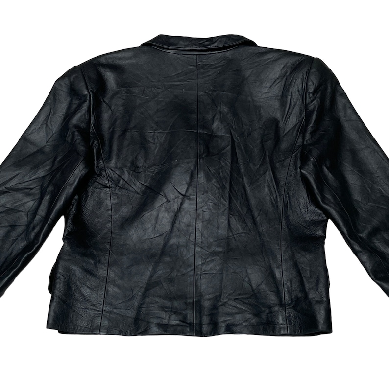 May include: A black leather jacket with a classic design. The jacket has a button closure and long sleeves.