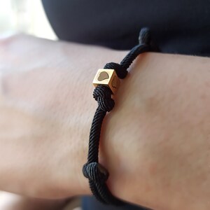 Pode incluir: Um bracelete de cordão preto com um fecho de ouro em forma de coração.