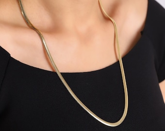 May include: A gold snake chain necklace. The chain is thin and delicate, and it is made of a smooth, shiny metal.