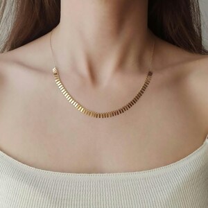 Puede incluir: Un collar de oro con una cadena delicada y un patrón graduado de eslabones rectangulares.