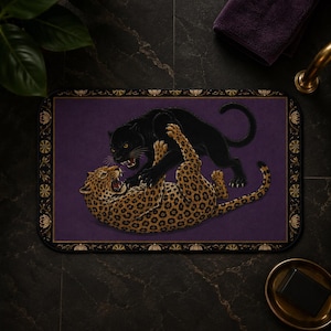 May include: A rectangular bath mat featuring a deep purple background with a decorative gold and black floral border. The center displays a detailed illustration of a black panther and a spotted leopard engaged in a dynamic wrestling pose.