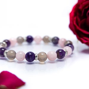 May include: A bracelet made with amethyst, rose quartz, and grey agate beads. The bracelet has silver accents between each bead.