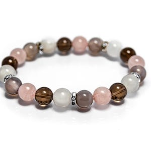 May include: A bracelet made with brown, pink, and white beads. The beads are strung on a silver chain.