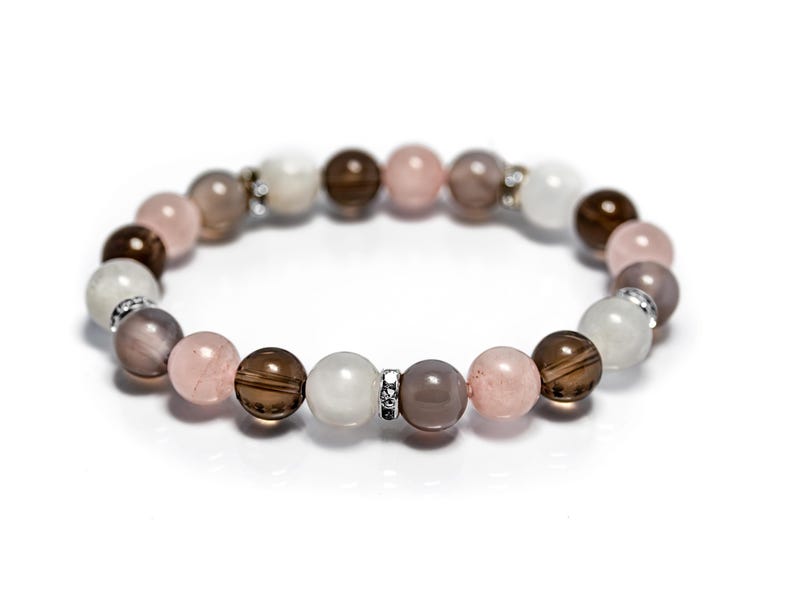 May include: A bracelet made with brown, pink, and white beads. The beads are strung on a silver chain.