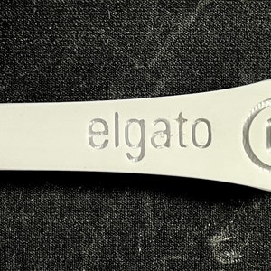 May include: White plastic key with the word "elgato" and a stylized "G" logo engraved on it.