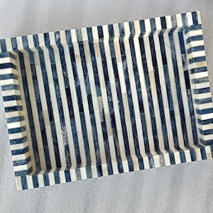 Könnte beinhalten: Ein rechteckiges Tablett mit einem schwarz-weißen Streifenmuster. Das Tablett ist aus Knochen gefertigt und hat einen leicht erhöhten Rand.