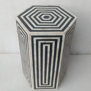 May include: Octagonal black and white geometric patterned side table. The table has a black and white geometric pattern on the top and sides.
