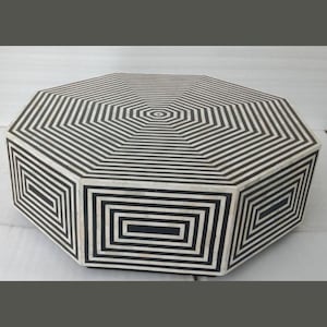 May include: Octagonal coffee table featuring a black and white geometric pattern crafted from bone inlay. The table boasts a distinctive design with concentric circles and squares.