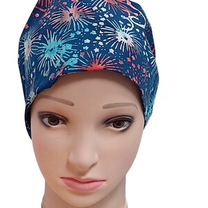 Puede incluir: Un gorro de quirófano azul con un patrón de fuegos artificiales blancos y rosas.
