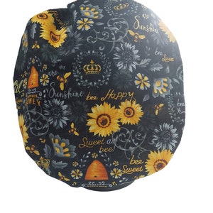 Peut inclure: Tissu noir avec un motif répété de tournesols, d'abeilles et de ruches. Le tissu porte l'inscription "You are my sunshine bee sweet", "Sunshine bee happy" et "Sweet as bee!" imprimée dessus.