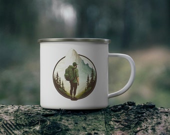 May include: White enamel camping mug featuring a graphic of a person hiking in a mountain landscape. The graphic is within a circle with green trees and a mountain in the background.