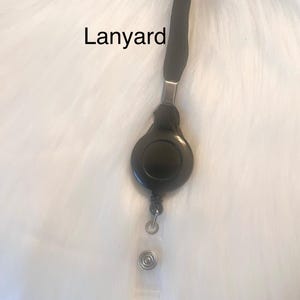 Puede incluir: Porta credenciales retr&aacute;ctil negro con un cord&oacute;n negro. El porta credenciales tiene un clip giratorio plateado y un resorte plateado.