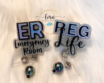 Può includere: Due rotoli di badge scintillanti in argento glitterato con testo nero. Il primo rotolo dice "ER Emergency Room" e il secondo rotolo dice "REG Life". Entrambi i rotoli hanno una perla nera e un clip per badge trasparente.