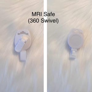 May include: Two white, MRI-safe badge reels with a 360-degree swivel feature. The reels have a round, flat surface with a clip on the back and a small strap for attaching a badge. The text "MRI Safe (360 Swivel)" is visible.