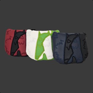May include: Three golf club head covers in red and black, white and green, and navy and black. Each cover features a stylized wolf design with decorative stitching. The covers are made of a leather-like material.