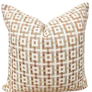 May include: A decorative throw pillow with a geometric pattern in shades of brown, beige, and white.