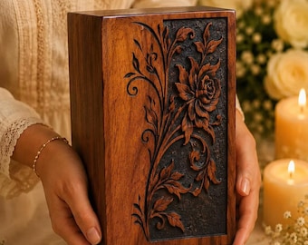 May include: A rectangular wooden box featuring a dark brown finish and a vertical panel with intricate, deep-relief carvings of a blooming flower and swirling vine patterns set against a textured, dark charcoal-colored background.