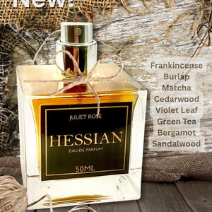 Puede incluir: Un frasco de vidrio cuadrado de Eau de Parfum "Hessian", con un líquido dorado en su interior. La etiqueta dice "Juliet Rose" y enumera ingredientes como incienso y sándalo. La botella está atada con hilo y es de 50 ml.
