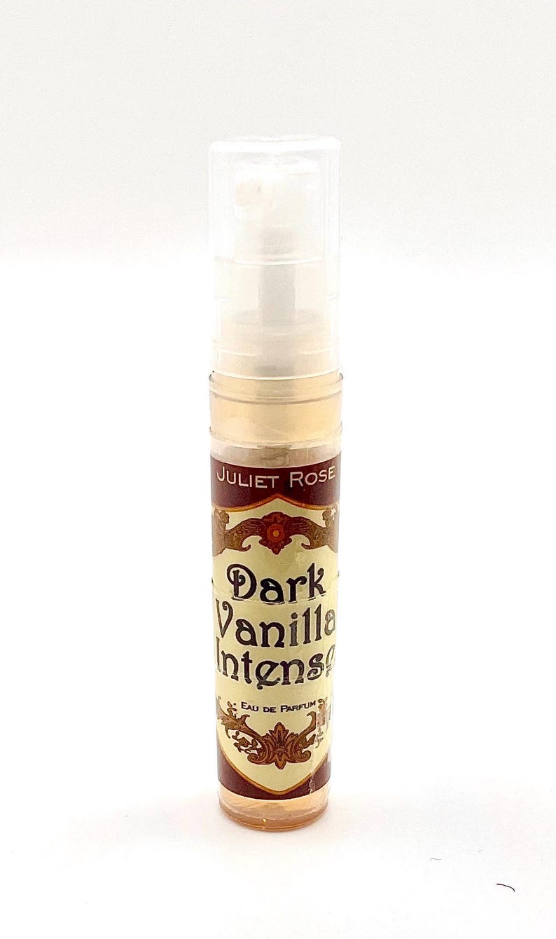 May include: A clear glass vial of "Dark Vanilla Intense" eau de parfum by Juliet Rose. The label is brown and gold with ornate lettering. The vial has a clear plastic cap and contains a light amber liquid.