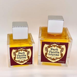 May include: Two glass perfume bottles with silver square caps. The bottles contain a yellow liquid and labels that read "Juliet Rose Dark Vanilla Intense". One bottle is labeled 50ml, the other 100ml.