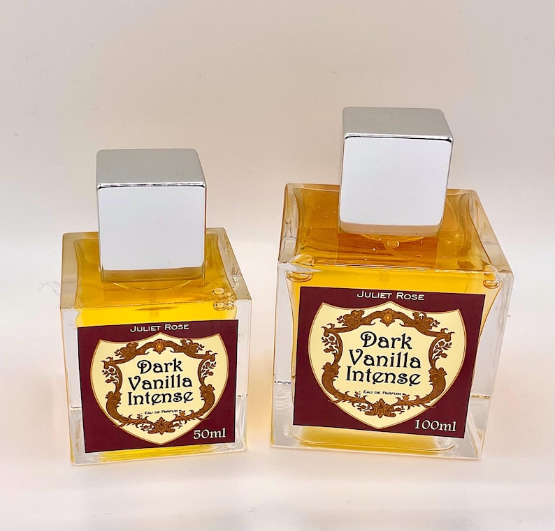 May include: Two glass perfume bottles with silver square caps. The bottles contain a yellow liquid and labels that read "Juliet Rose Dark Vanilla Intense". One bottle is labeled 50ml, the other 100ml.