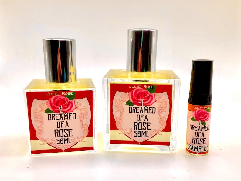 Puede incluir: Tres botellas de perfume de vidrio con tapas plateadas. Las botellas est&aacute;n etiquetadas con "Juliet Rose" y "So&ntilde;&eacute; con una rosa". La botella m&aacute;s peque&ntilde;a est&aacute; etiquetada con "Muestra".