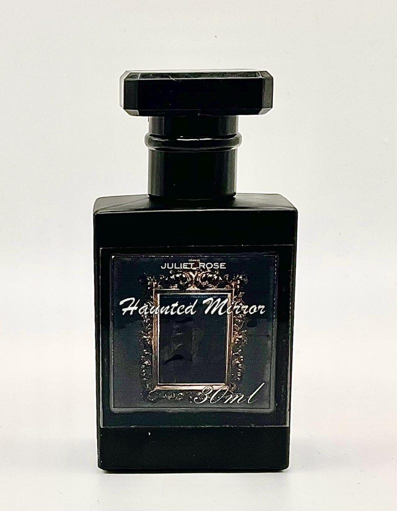 May include: A black rectangular perfume bottle with a matching cap. The label reads "JULIET ROSE Haunted Mirror" with a decorative frame and the volume is 30ml.