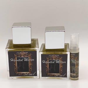 May include: Two square glass perfume bottles with silver caps and a small sample bottle. The labels read "JULIET ROSE Haunted Mirror 30ml". The perfume inside the bottles is a light olive green color.