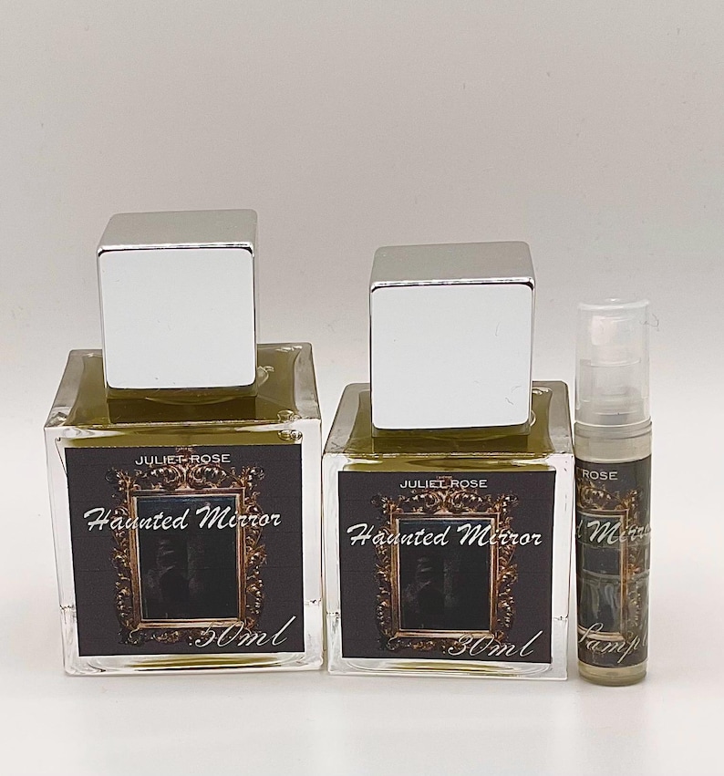 May include: Two square glass perfume bottles with silver caps and a small sample bottle. The labels read "JULIET ROSE Haunted Mirror 30ml". The perfume inside the bottles is a light olive green color.