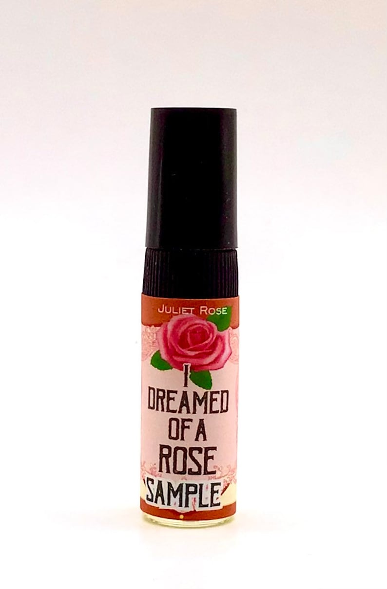Puede incluir: Una peque&ntilde;a botella de vidrio transparente con una tapa negra y una etiqueta que dice "I Dreamed of a Rose" con una ilustraci&oacute;n de rosa rosa. La etiqueta tambi&eacute;n dice "Juliet Rose" y "Sample".