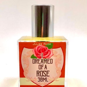 Puede incluir: Una botella de vidrio transparente con una tapa plateada y una etiqueta que dice "JULIET ROSE I DREAMED OF A ROSE 30ML". La etiqueta es naranja con una ilustraci&oacute;n de rosa rosa.
