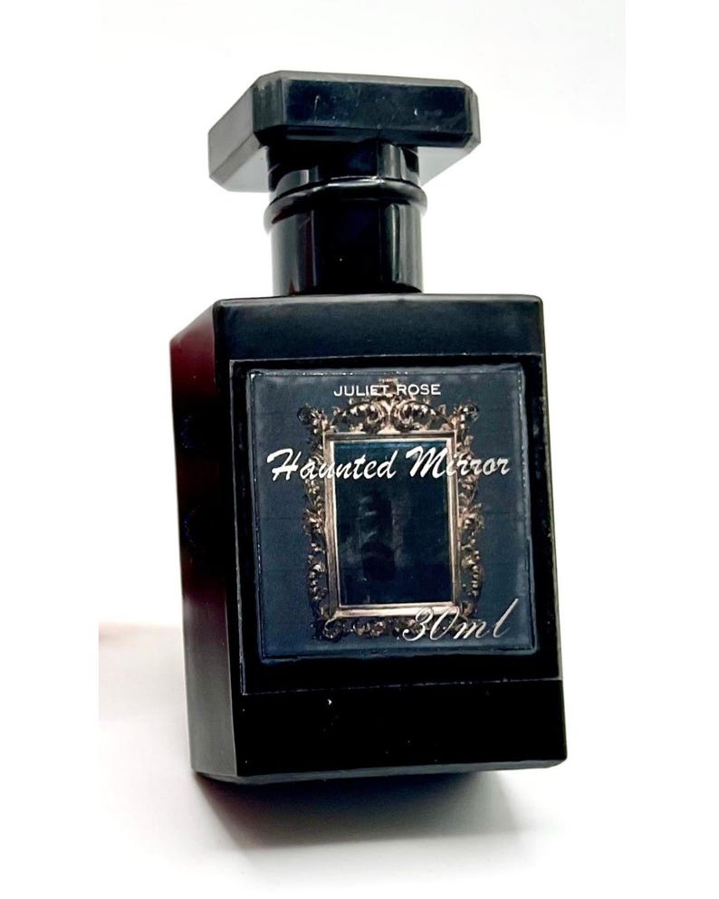 May include: A black rectangular perfume bottle with a matching cap. The label reads "Juliet Rose Haunted Mirror" with a decorative frame. The bottle contains 30ml of perfume.