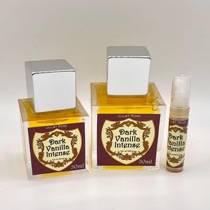 May include: Three perfume bottles with silver caps. Two square bottles are labelled "Dark Vanilla Intense" with 30ml and 50ml sizes. A smaller spray bottle is also labelled "Dark Vanilla Intense". The bottles contain a yellow liquid.