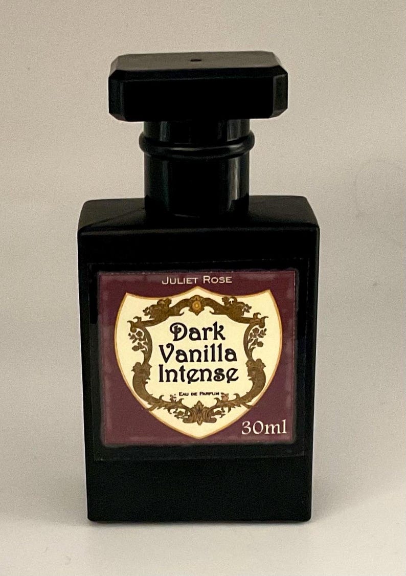 May include: A black rectangular perfume bottle with a black cap. The label reads "Juliet Rose Dark Vanilla Intense" with a decorative design. The bottle contains 30ml of perfume.