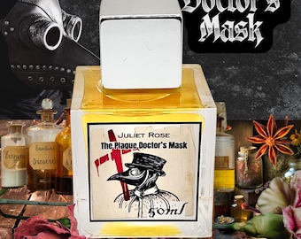May include: A square glass perfume bottle with a silver cap containing yellow liquid. The label features the text Juliet Rose, The Plague Doctor's Mask, and 50ml, along with a black and white illustration of a plague doctor wearing a top hat.