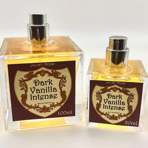 May include: Two glass perfume bottles with silver spray tops. The bottles are filled with a golden liquid and have labels that read "Juliet Rose Dark Vanilla Intense Eau de Parfum". The larger bottle is 100ml, the smaller is 30ml.