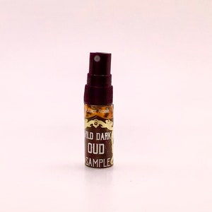 May include: A small brown bottle with a dark brown cap and a gold label that reads "Wild Dark Oud Sample".
