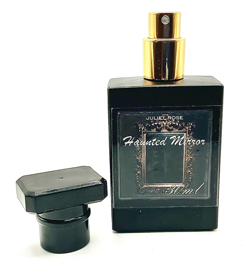 May include: A black rectangular perfume bottle with a gold-colored sprayer and a separate black cap. The label reads "JULIET ROSE Haunted Mirror 30ml". The bottle is on a white background.