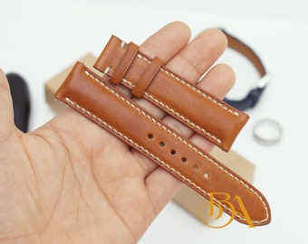 May include: Two brown leather watch straps with white stitching. The straps are laid out on a hand.