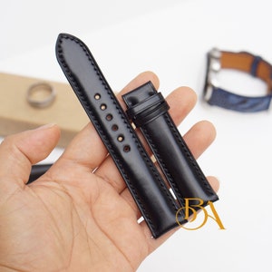 May include: Two black leather watch straps with stitching detail. The straps are laid out on a hand.