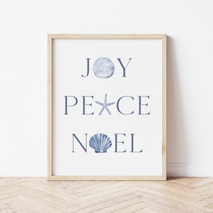 Puede incluir: Una impresi&oacute;n enmarcada con las palabras "JOY PEACE NOEL" en texto azul. Cada palabra est&aacute; decorada con una concha diferente.