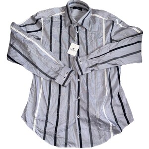 May include: A light gray button-down shirt with vertical stripes in black, white, and darker gray. The long-sleeved shirt has a classic collar and buttoned cuffs. A tag with a logo hangs near the buttons.