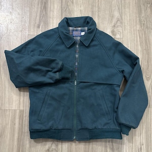 May include: A teal-colored jacket with a collared neckline and a full zipper closure. The jacket features a ribbed hem and cuffs, and two front pockets. The interior lining has a plaid pattern. The jacket is made of a soft, durable material.