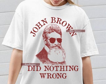 May include: White t-shirt with a red illustration of John Brown wearing sunglasses and a beard. The text "John Brown Did Nothing Wrong" is printed on the shirt.