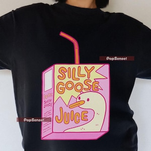 May include: A black t-shirt with a pink and yellow cartoon illustration of a goose inside a juice box. The juice box has the words 