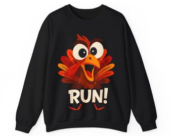 Puede incluir: Sudadera negra con un diseño de pavo de dibujos animados. El pavo tiene el pico muy abierto y la palabra "RUN!" en blanco. Las plumas del pavo son rojas, naranjas y marrones, con ojos grandes. Un diseño divertido y festivo para las fiestas.