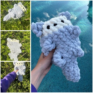 May include: A soft, plush, crocheted toy in the shape of a creature with large eyes and a white patch on its head. The toy is light blue and has a fluffy texture.
