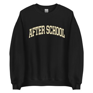 May include: Black sweatshirt with the text "AFTER SCHOOL" in a cream-colored, arched font. The sweatshirt is a crew neck style, made of a soft material. The Gildan brand tag is visible at the neckline.