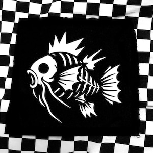 Pode incluir: Etiqueta termocolante preta e branca com um peixe esquelético estilizado com uma barbatana espinhosa. O peixe é delineado em branco sobre um fundo preto.
