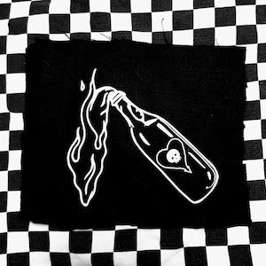 Könnte beinhalten: Ein schwarzer Patch mit einer weißen Umrandung einer Flasche, aus der Flüssigkeit fließt. Die Flasche hat ein Herz mit einem Schädel darin.